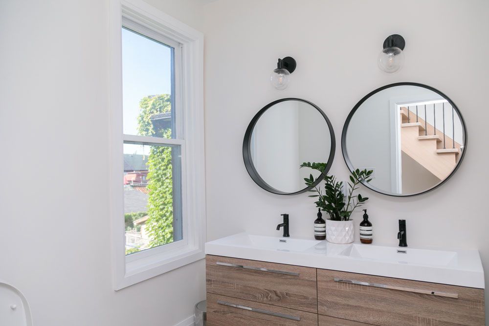 A bathroom remodel with two sinks , two mirrors and a window.