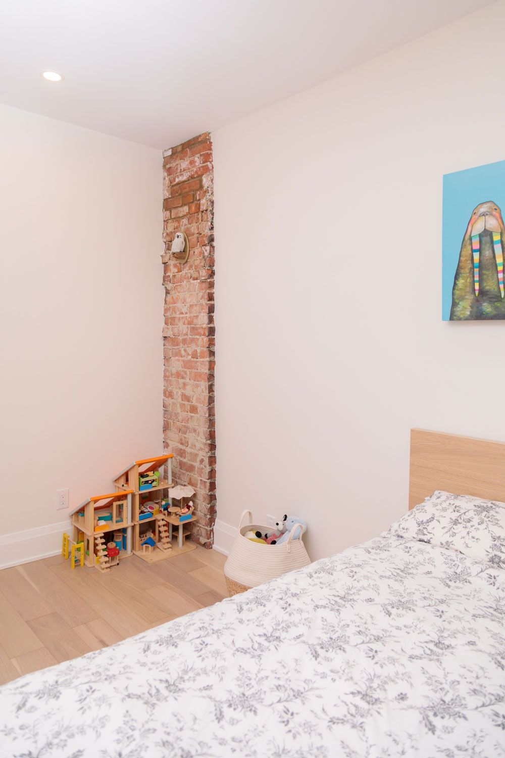 A third-story addition bedroom with a bed, a doll house, and a painting on the wall.