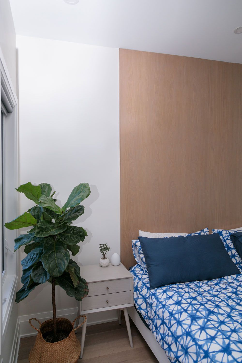 A third-story addition bedroom with a bed, nightstand, and plant.