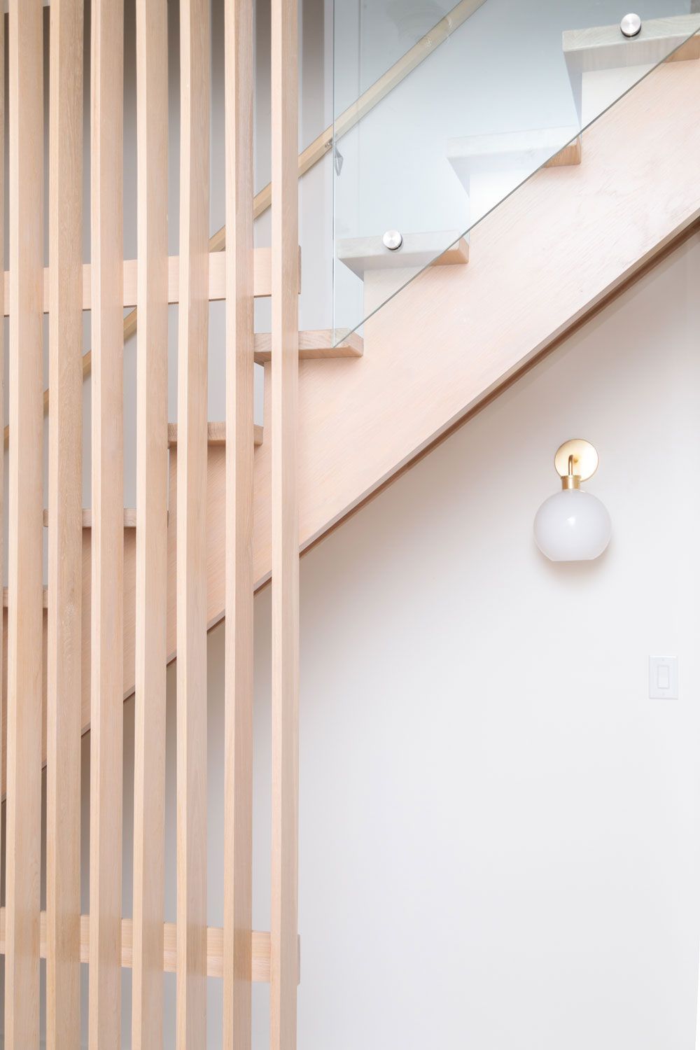 A staircase with a wooden railing and a glass railing.
