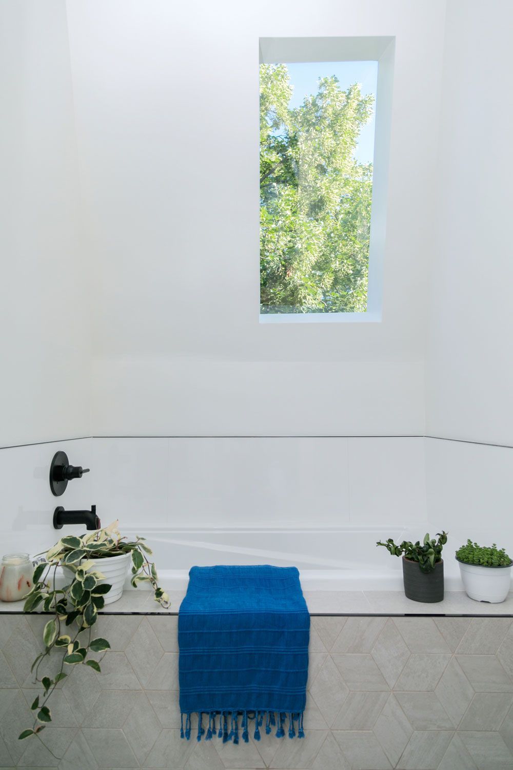 A bathroom remodel with a blue towel sitting on top of a bathtub next to a window.