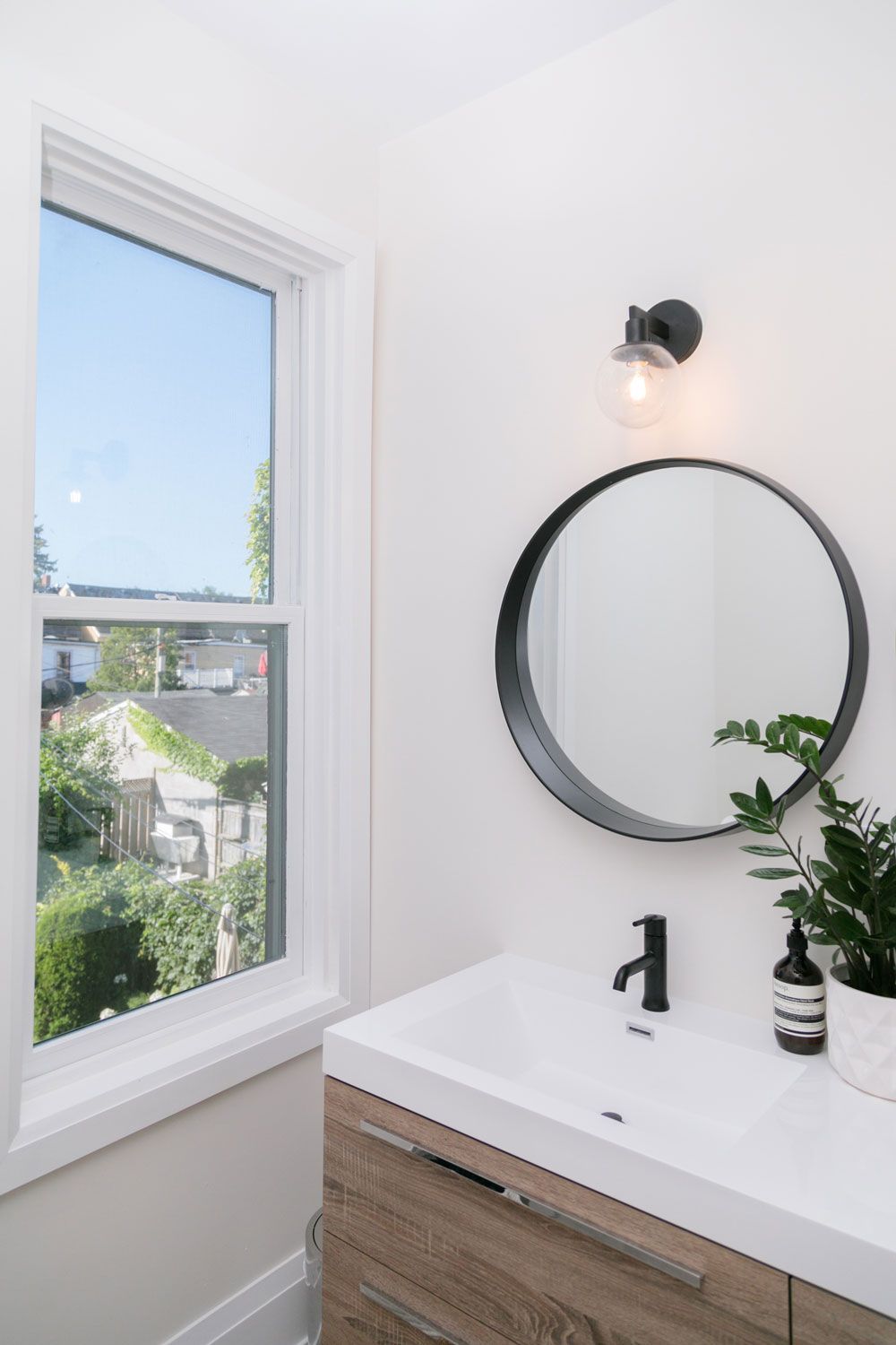 A bathroom remodel with a sink , mirror and window.