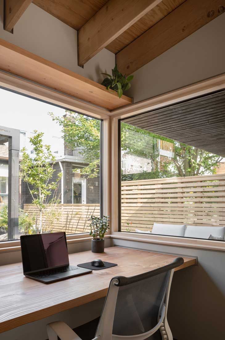 A desk with a laptop on it and a chair in front of a window.