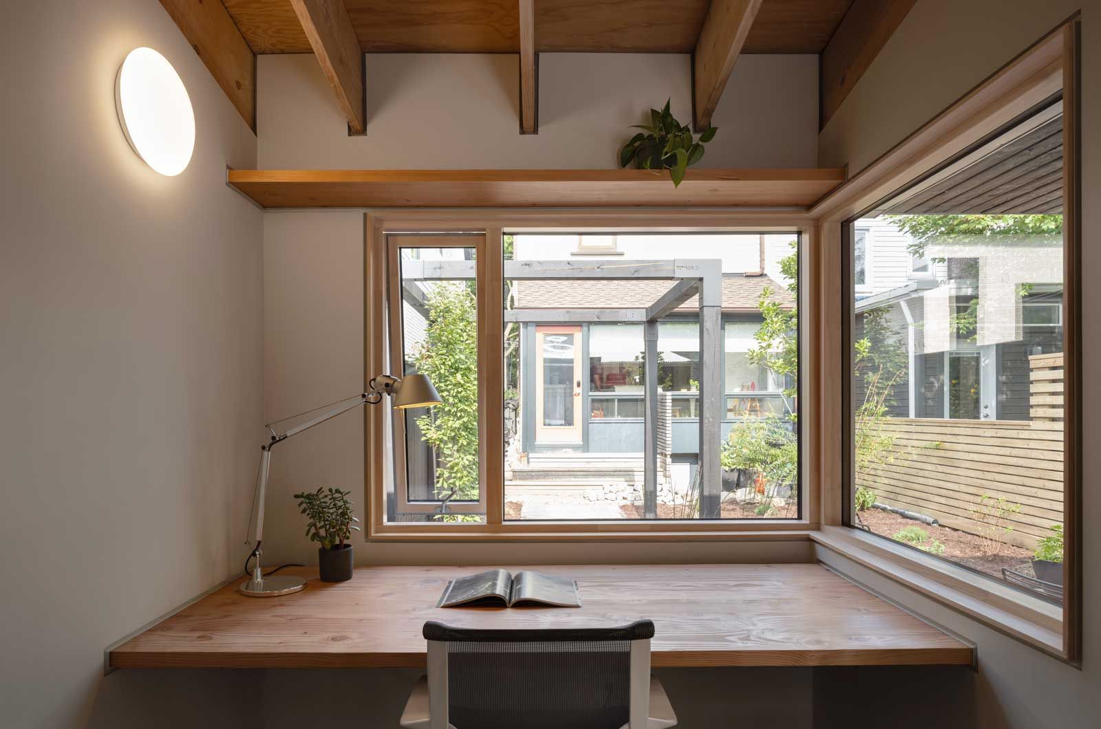 There is a desk with a book on it in front of a window.