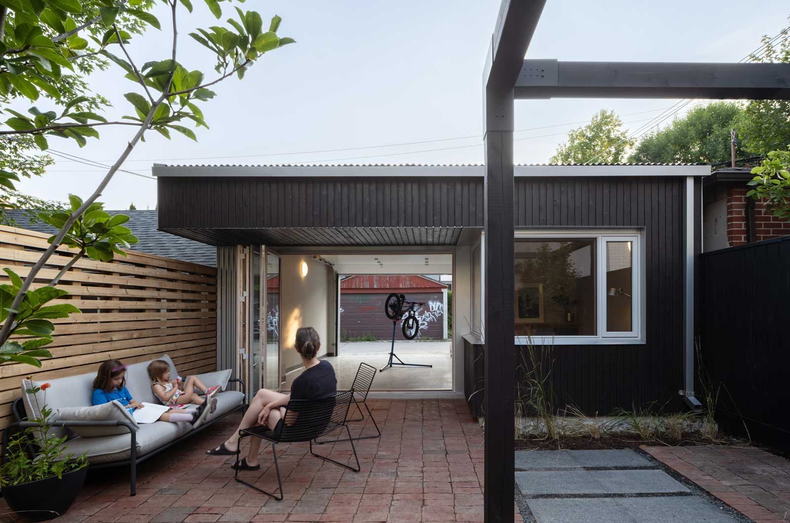 A group of people are sitting on a patio in front of a house.