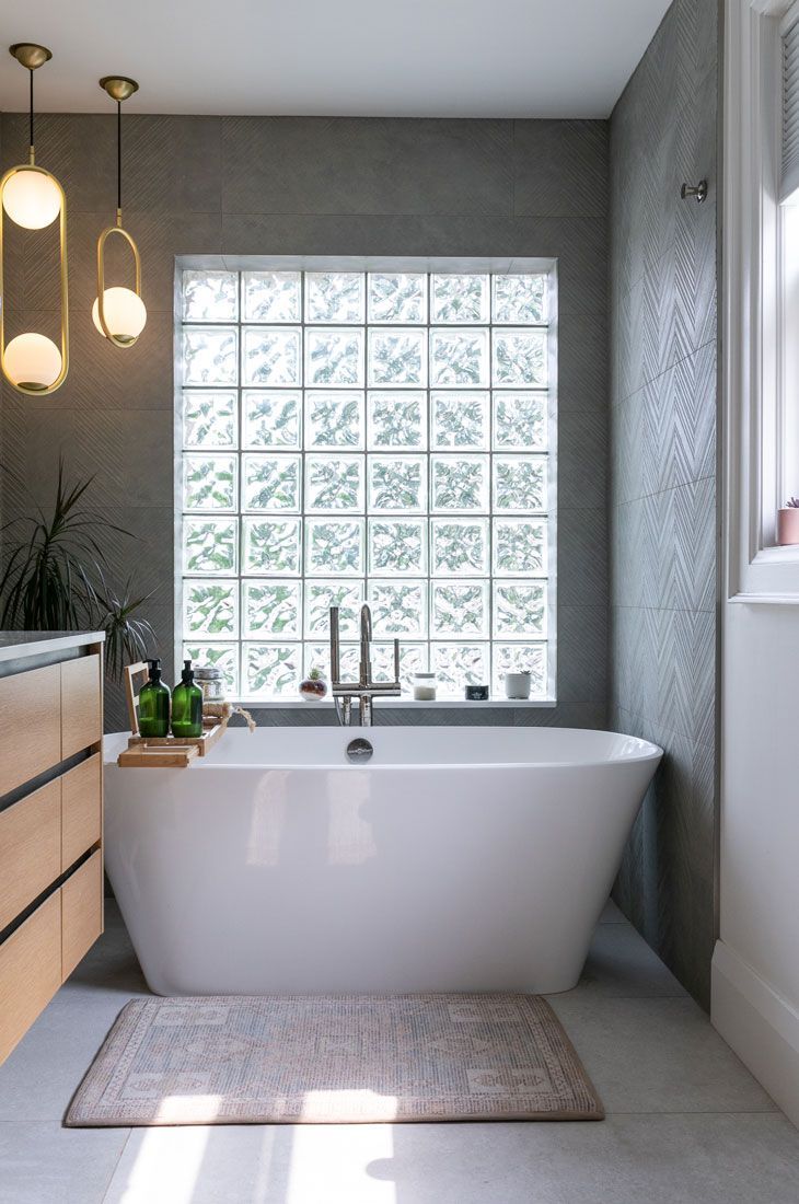 A bathroom remodel with a bathtub and a window with glass blocks.