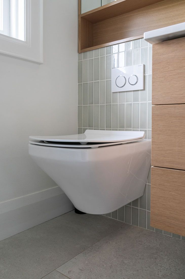A white toilet is hanging on the wall in a bathroom remodel.