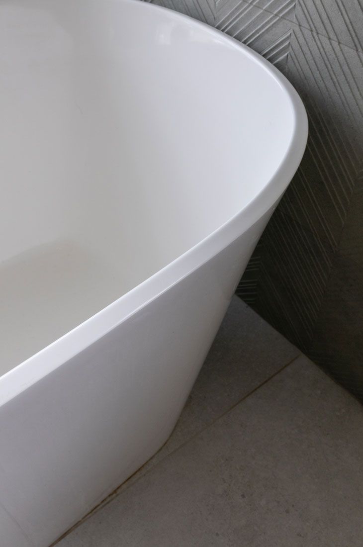 A white bathtub is sitting on a tiled floor in a bathroom remodel.