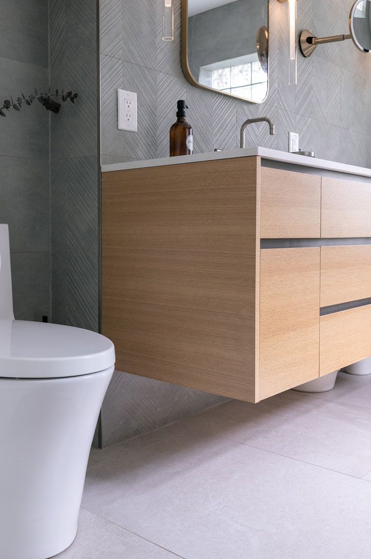 A bathroom remodel with a toilet, sink, and mirror.