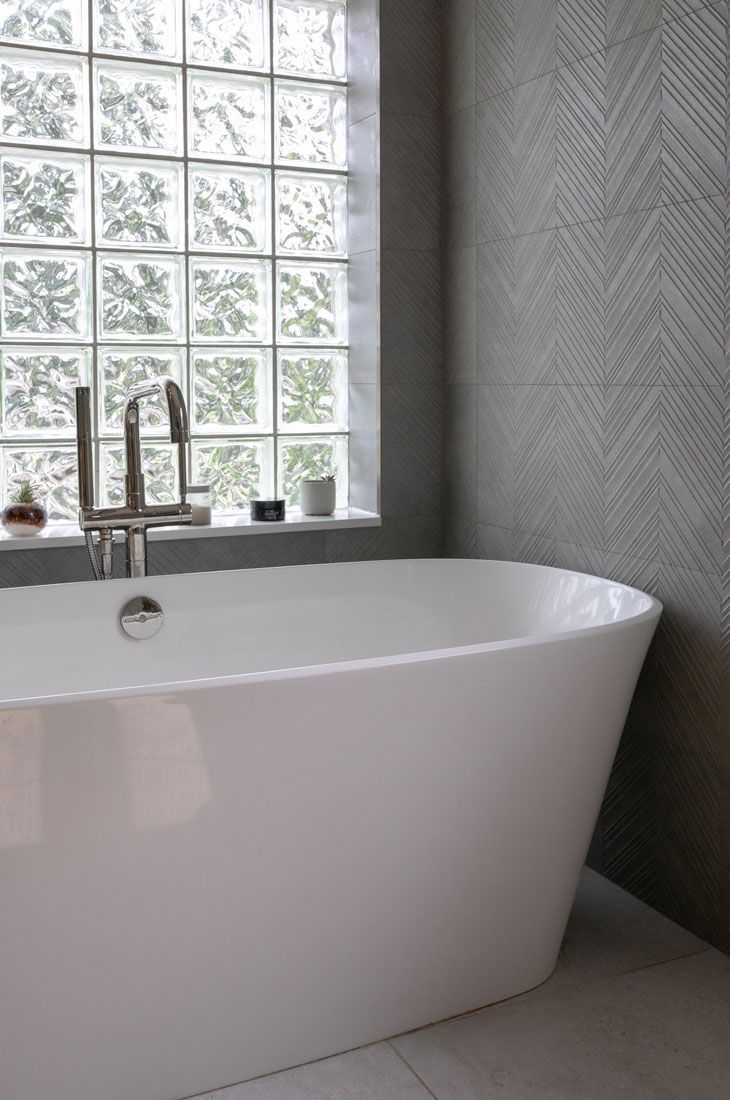 A white bathtub is sitting in a bathroom next to a window.