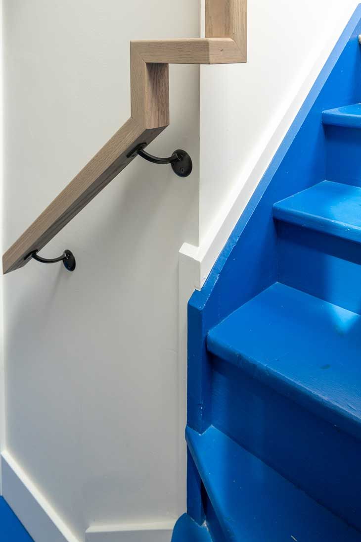 A blue staircase with a wooden hand rail