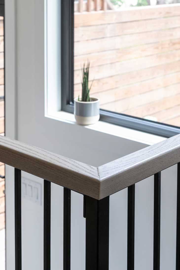 A potted plant is sitting on a window sill next to a railing.