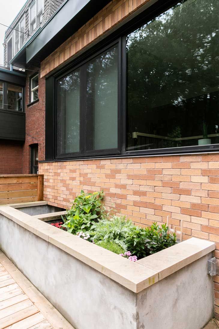 A brick building with a window and a planter in front of it.