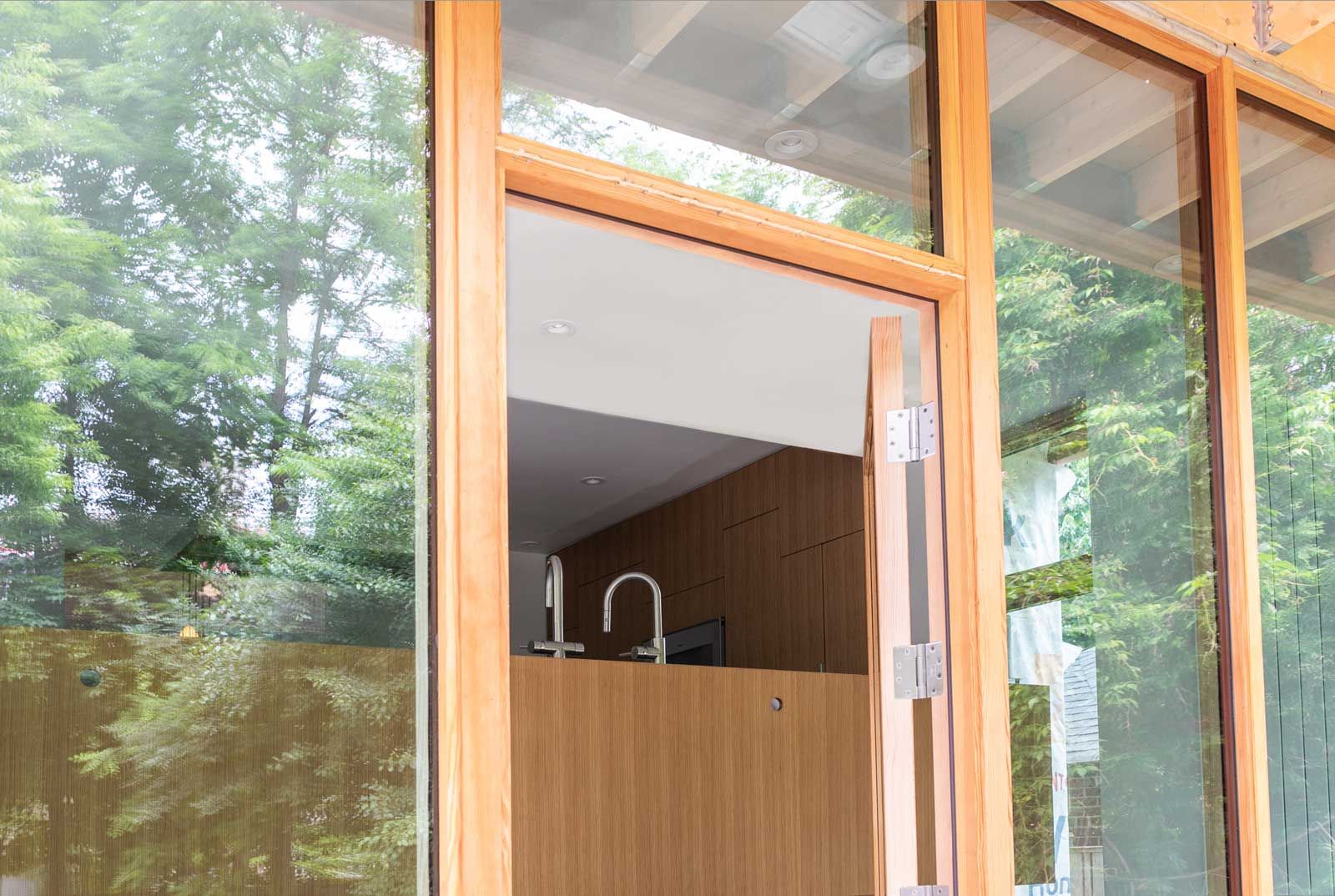 A large window with a wooden frame is open to a kitchen.