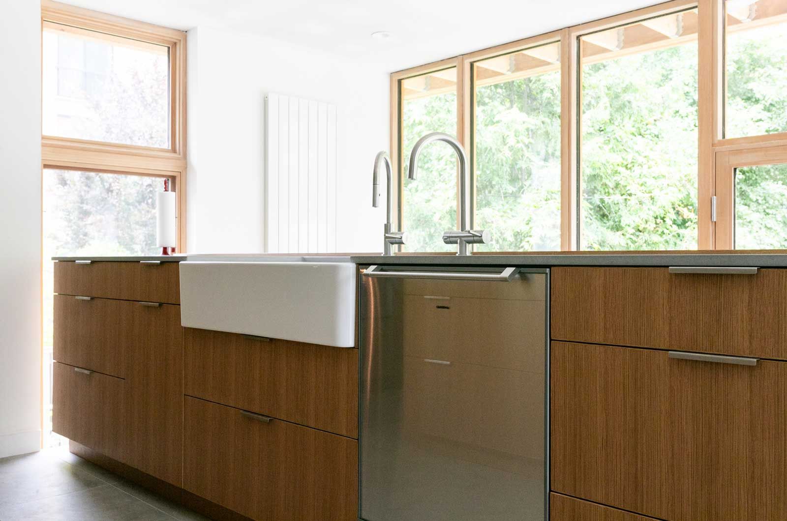 A kitchen with a sink , dishwasher , and large windows.