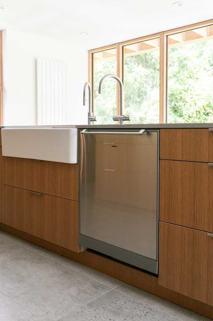 A kitchen with stainless steel appliances , wooden cabinets , a sink and a dishwasher.