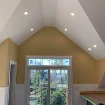 A room with a vaulted ceiling and a large window.