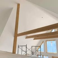 A room with white walls and wooden beams and scaffolding.
