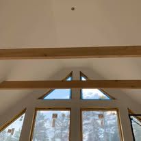 The ceiling of a room with a lot of windows and wooden beams.