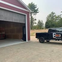 A truck is parked in front of a red garage door.