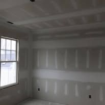 A room with a window and drywall on the walls.