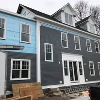 A blue and a gray house are being built next to each other.