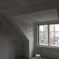 A room with a window and a bucket of paint in it.