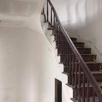 A wooden staircase with a metal railing in a white room.