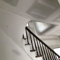 A staircase with a wooden railing in a house under construction.