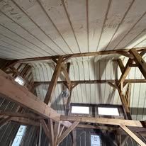 The inside of a barn with a wooden ceiling and beams.