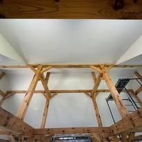 Looking up at the ceiling of a barn with wooden beams.