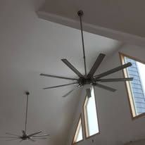 Two ceiling fans are hanging from the ceiling in a room with windows.