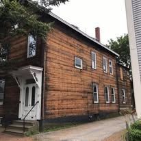 A large wooden house with a white door and stairs.