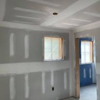 A room with drywall on the walls and a window.