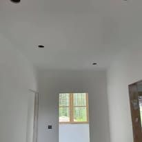 A hallway with white walls and a window in a house.