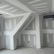 A room with a slanted ceiling and drywall on the walls.