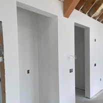 A room with white walls and wooden beams in a house under construction.