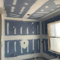 A room with a ceiling that is being plastered and a window.