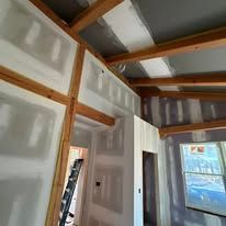 A room with drywall walls and a ladder in it.