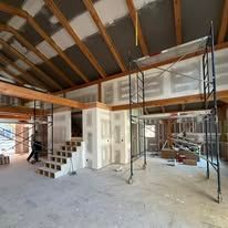 A large room with stairs and scaffolding in it is being remodeled.