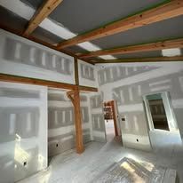 A room with drywall on the walls and wooden beams.