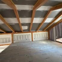 The ceiling of a room with wooden beams and drywall.