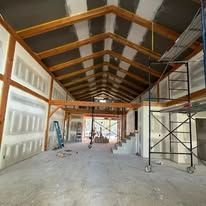 A large room with a wooden ceiling and stairs in a building under construction.
