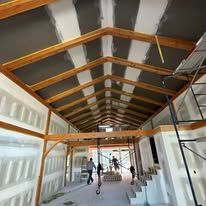 A long hallway with a wooden ceiling and stairs in a building under construction.