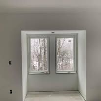 A room with two windows in it and a view of trees.