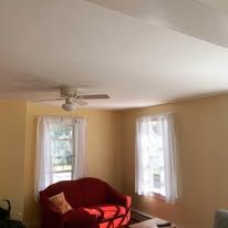 A living room with a red couch and a ceiling fan.