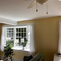 A living room with a ceiling fan and a window.