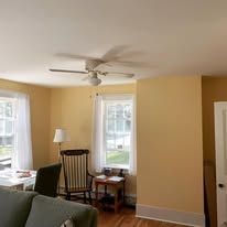 A living room with a couch , chair , table and ceiling fan.