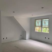 An empty room with two windows and a slanted ceiling.