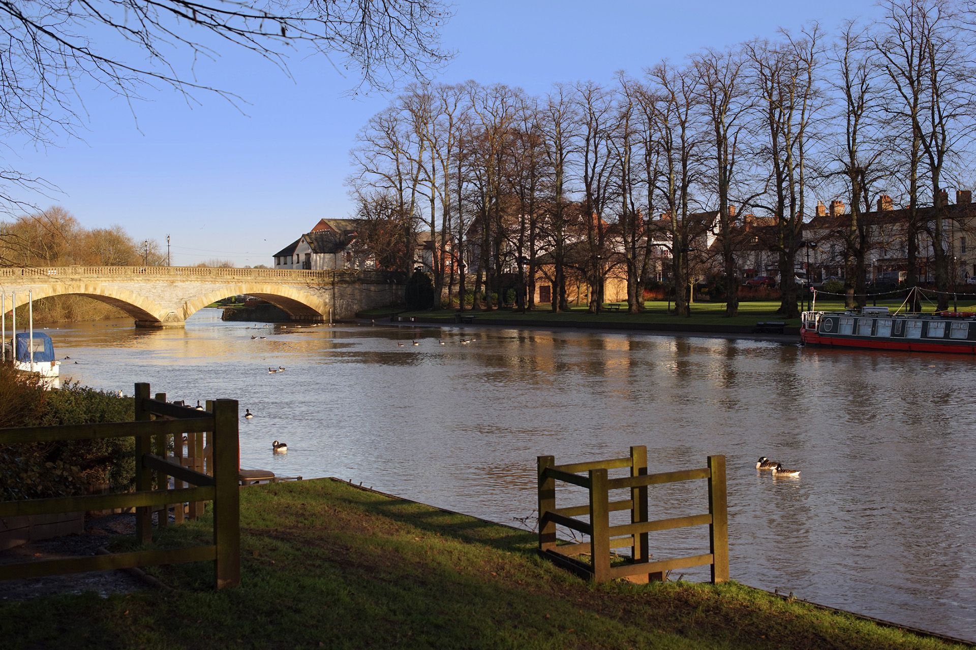 A river with a bridge in the background and a fence in the foreground